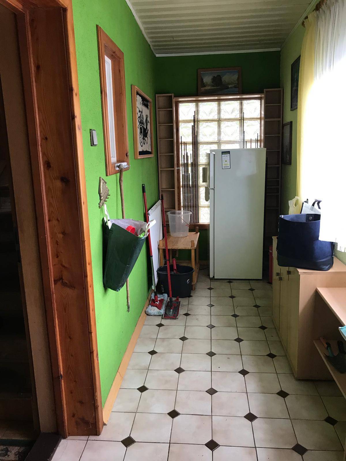 Grüner Flur mit gefliestem Boden, einem Kühlschrank und Regalen für zusätzlichen Stauraum.
