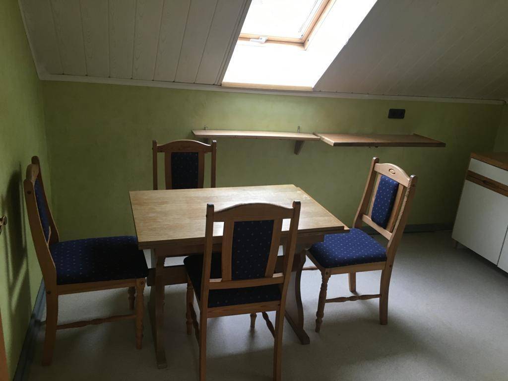 Essbereich im Dachgeschoss mit Holztisch, Stühlen, schräger Decke und einem Dachfenster.