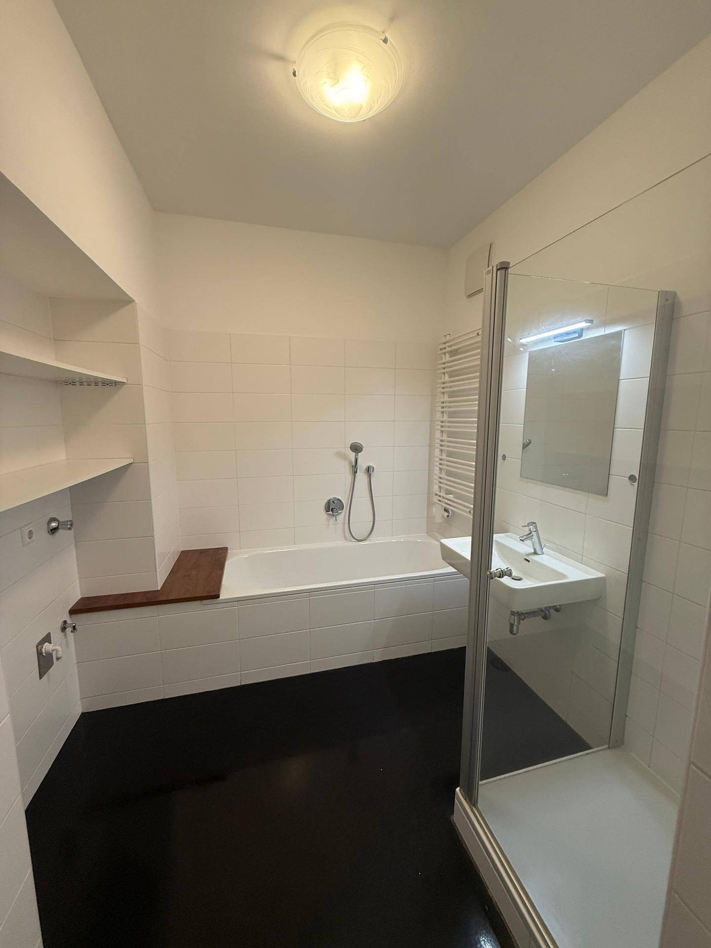 Geräumiges Badezimmer mit Badewanne, Duschkabine, Einzelwaschbecken und praktischen Ablageflächen.