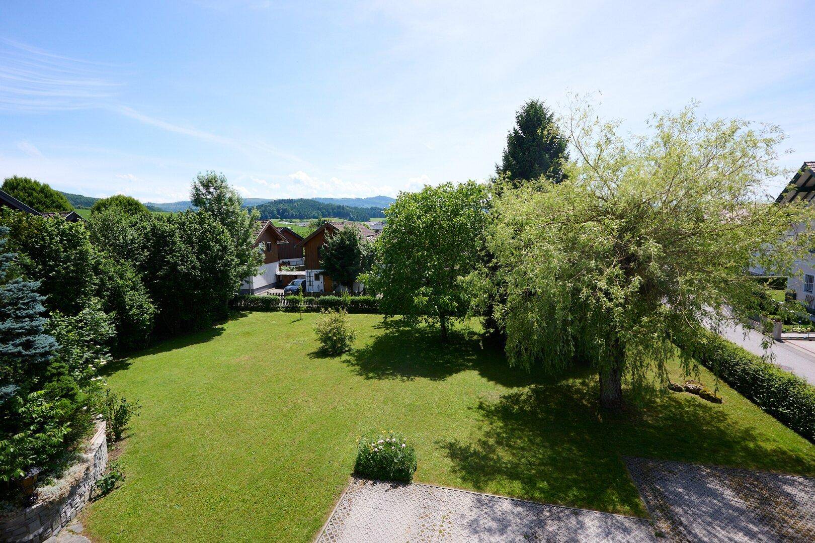 Weitläufiger Garten mit gepflegtem Rasen und Bäumen, bietet einen schönen Blick in die Landschaft.