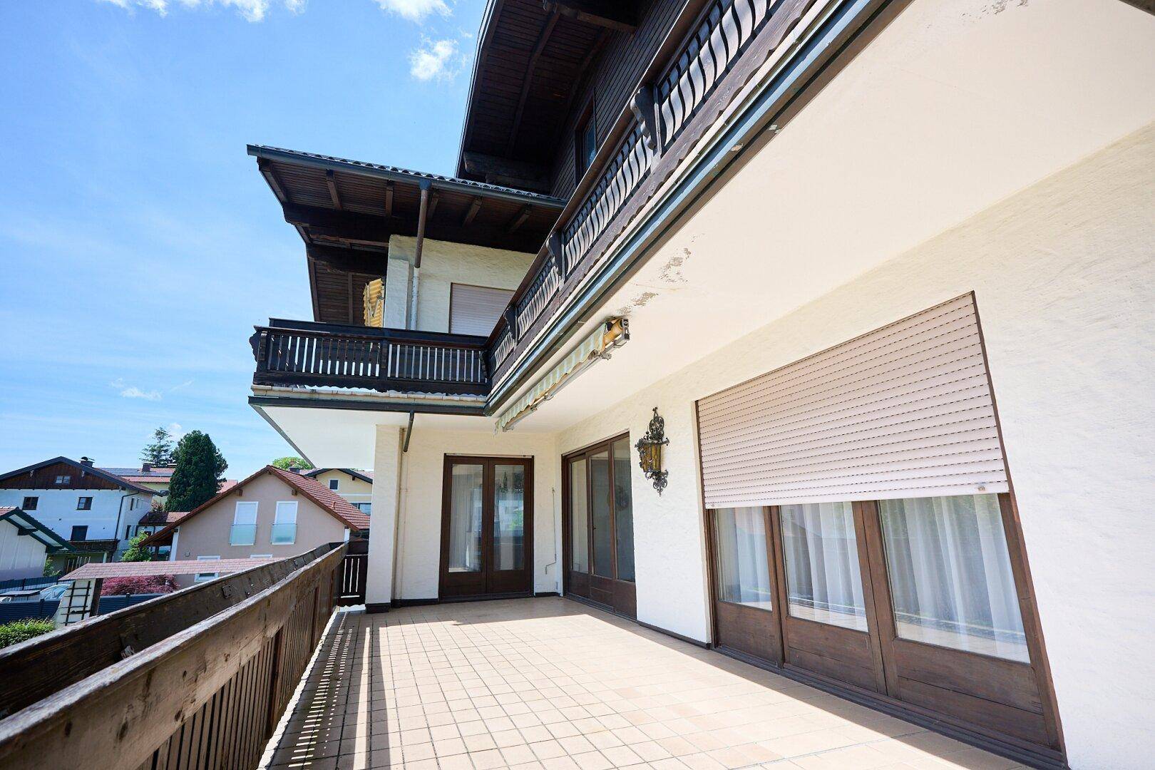 Großer Balkon mit Fliesenboden und Holzgeländer, bietet viel Platz im Freien und weite Aussicht.