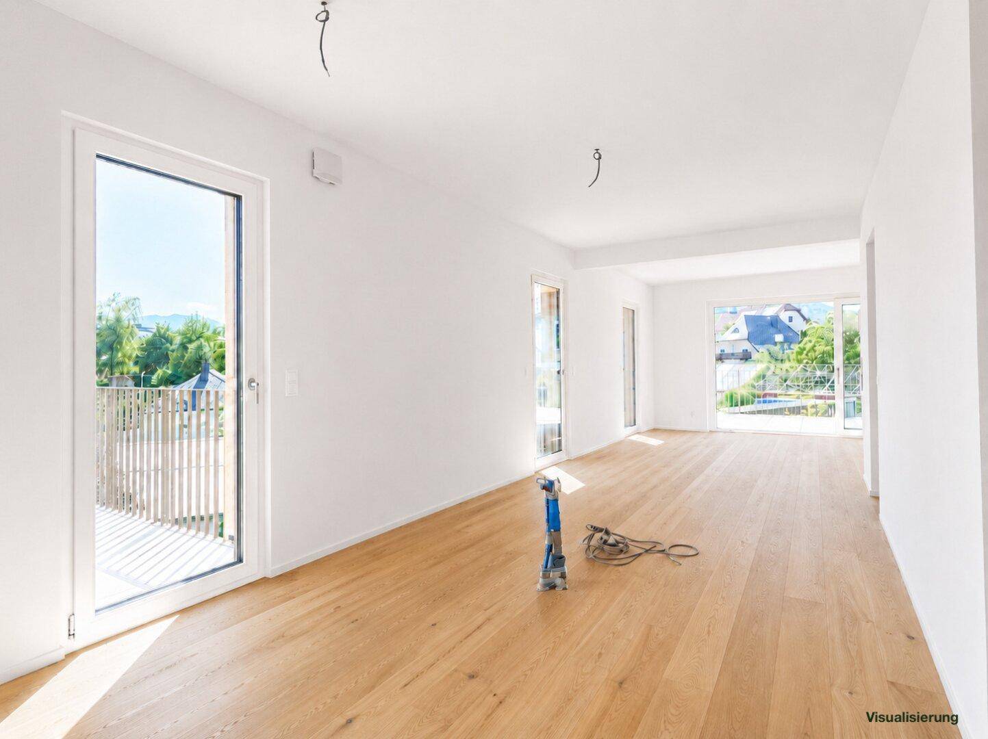 Lichtdurchfluteter Raum mit Holzboden, großen Fenstern und Zugang zu einem Balkon.