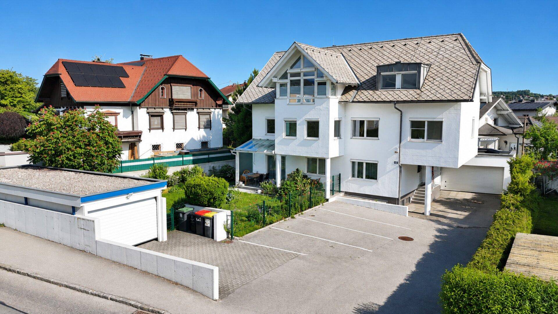 Attraktives Wohnhaus mit mehreren Parkplätzen, gepflegtem Gartenbereich und moderner Architektur.