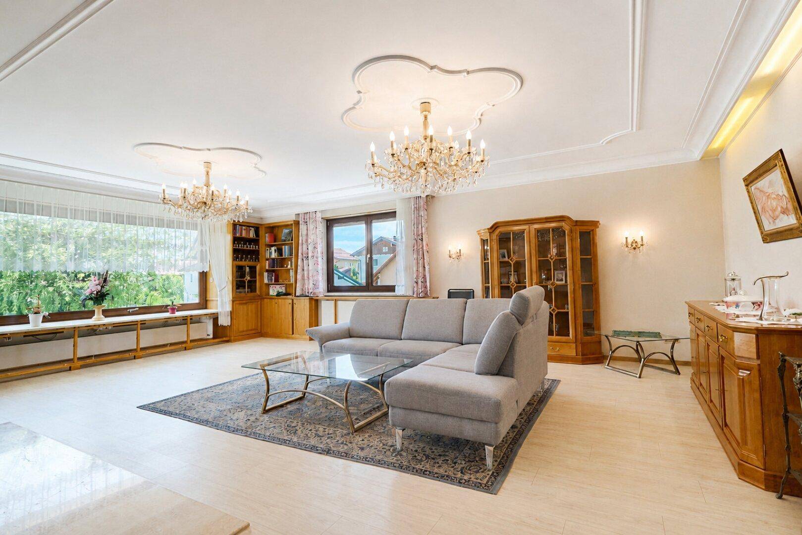 Elegantes Wohnzimmer mit Stuckdecken, Kronleuchtern und klassischem Mobiliar, das eine luxuriöse Atmosphäre schafft.