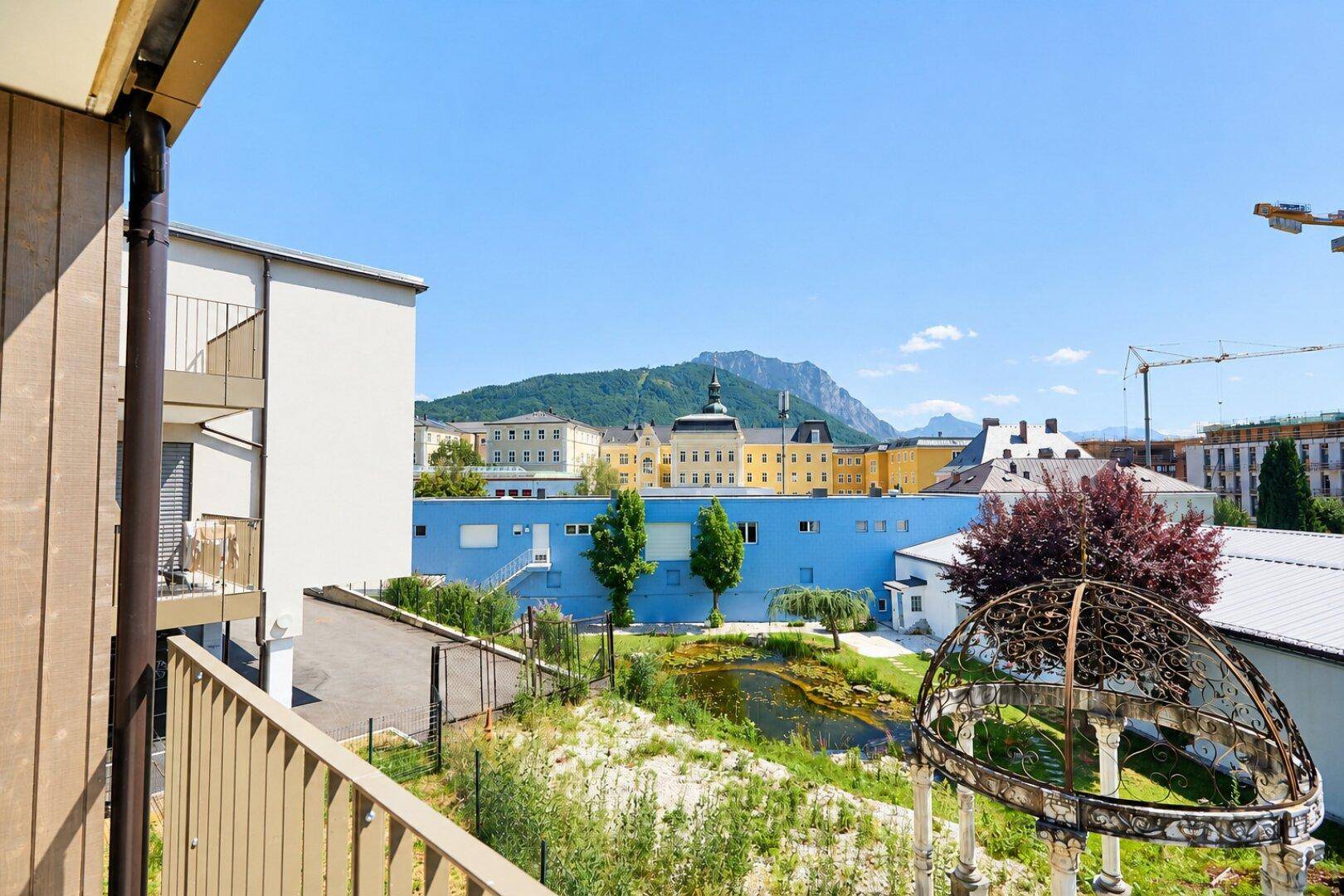 Panoramablick vom Balkon auf die Stadt, grüne Umgebung und die umliegenden Berge.
