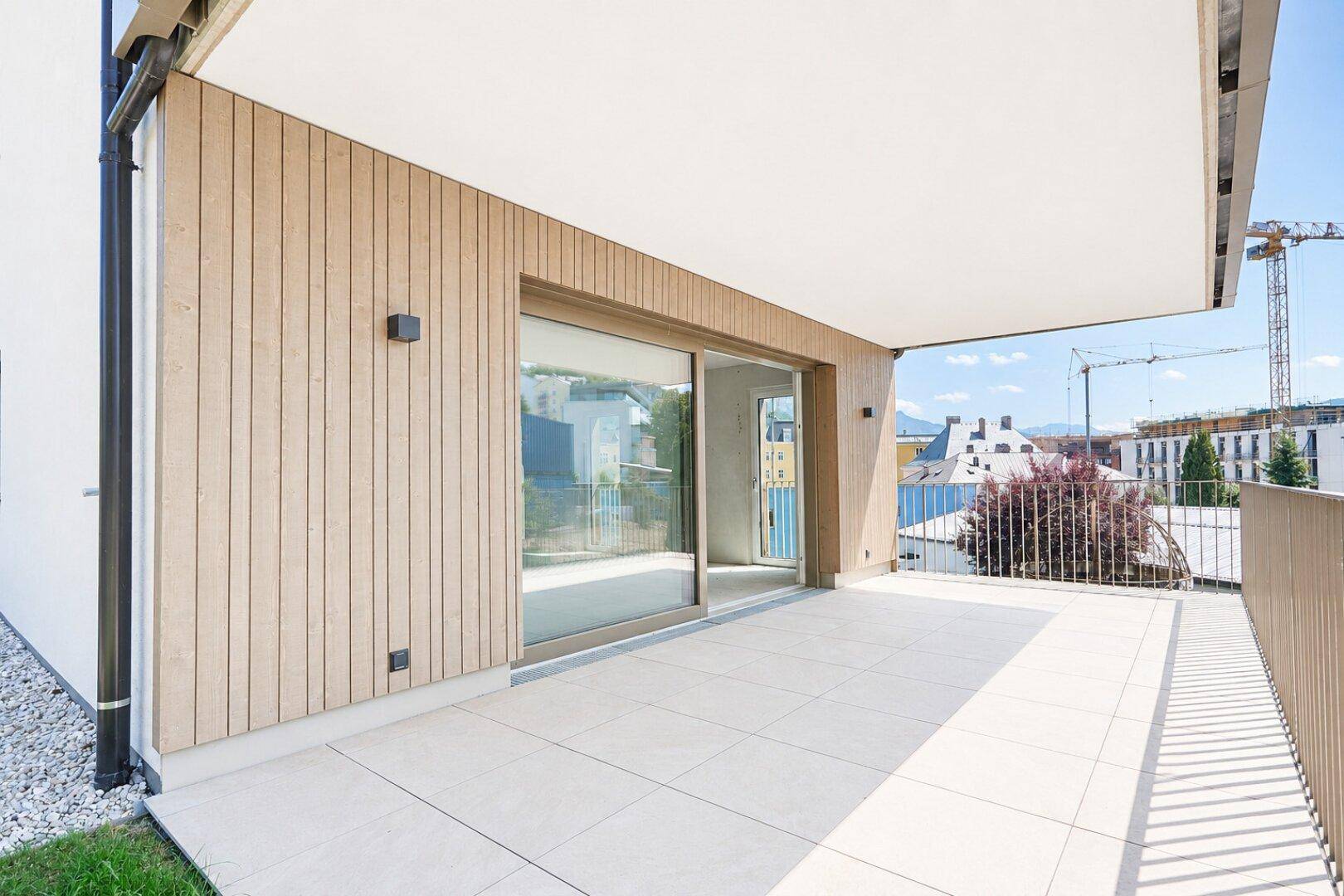 Große, moderne Terrasse mit Fliesenboden und Holzverkleidung, ideal für Entspannung im Freien.