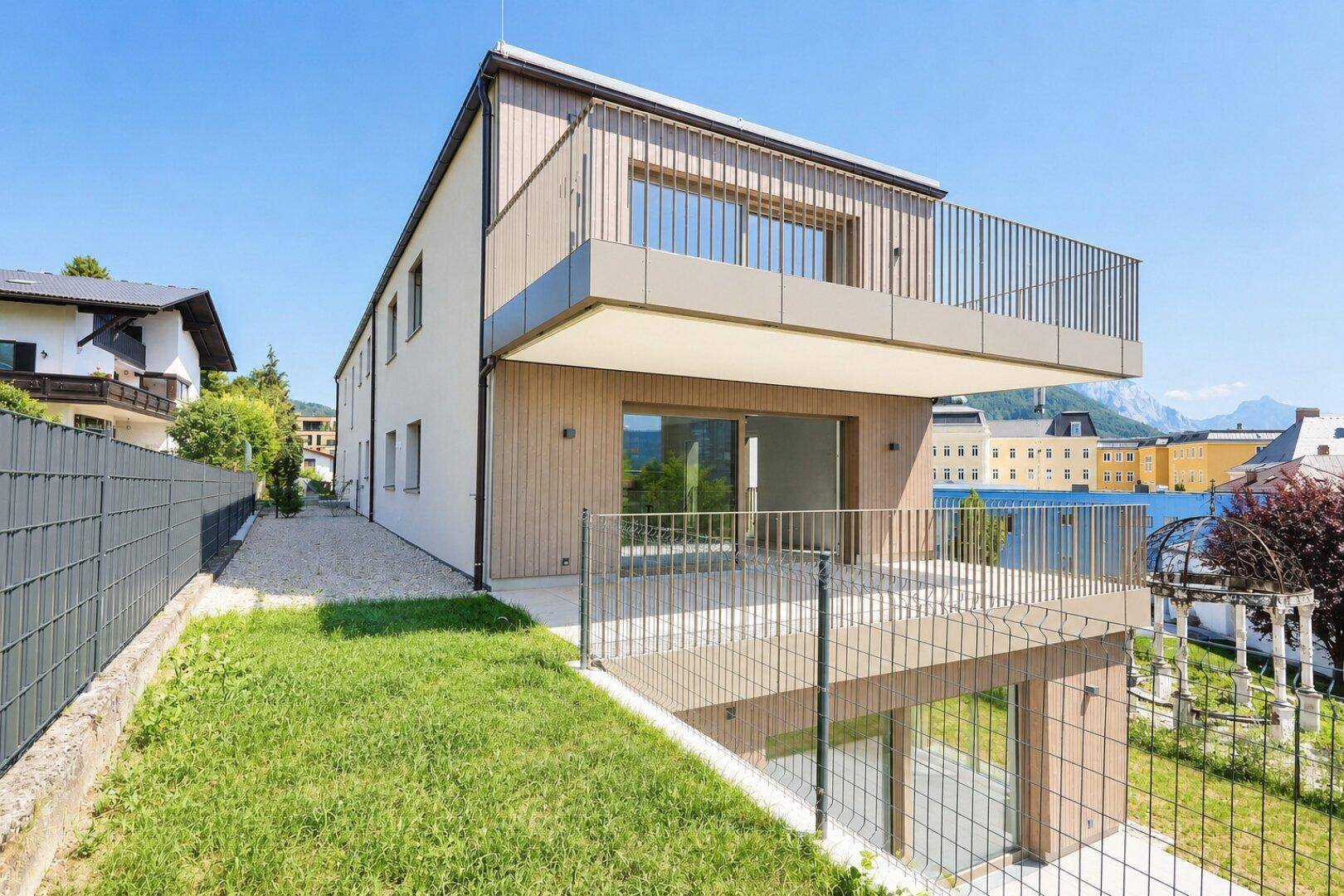 Moderne Architektur des Neubaus mit Holzverkleidung, Balkonen und Terrassenbereichen.