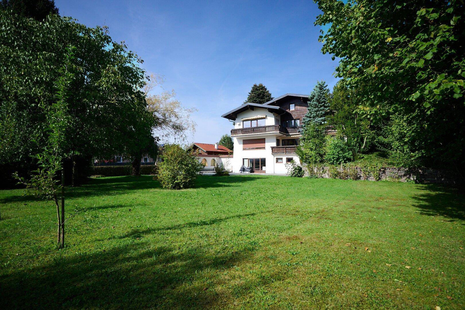 Großer, gepflegter Garten mit weitläufiger Rasenfläche und altem Baumbestand rund um das Haus.