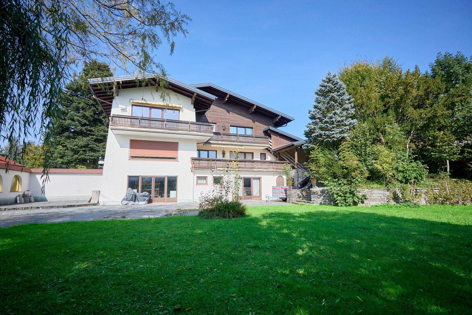 Ansicht des Hauses vom Garten aus mit Fassade, Balkonen und üppigem Grün.