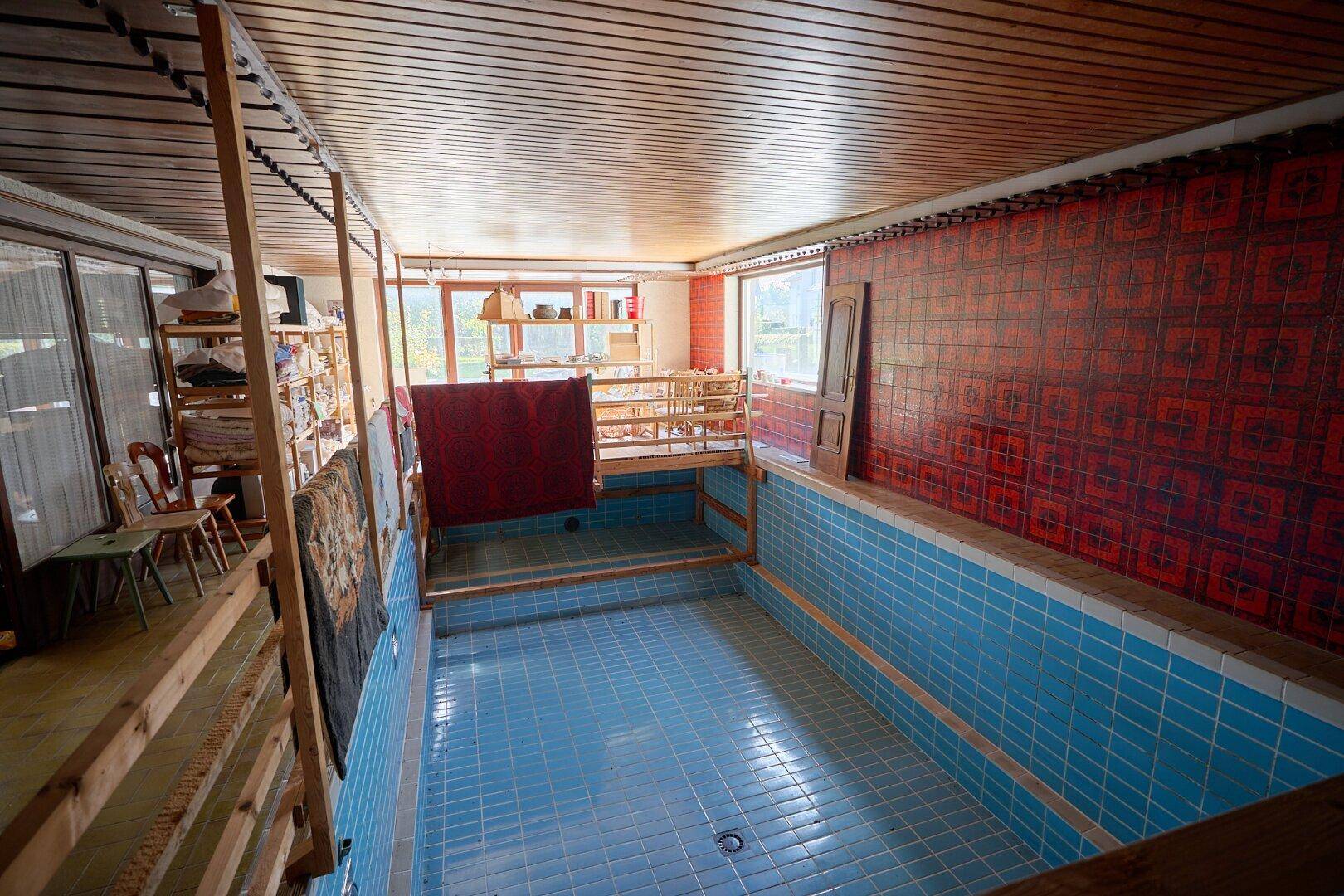 Innenpoolbereich mit blauen Fliesen, Holzdecke und auffälliger Wandgestaltung.
