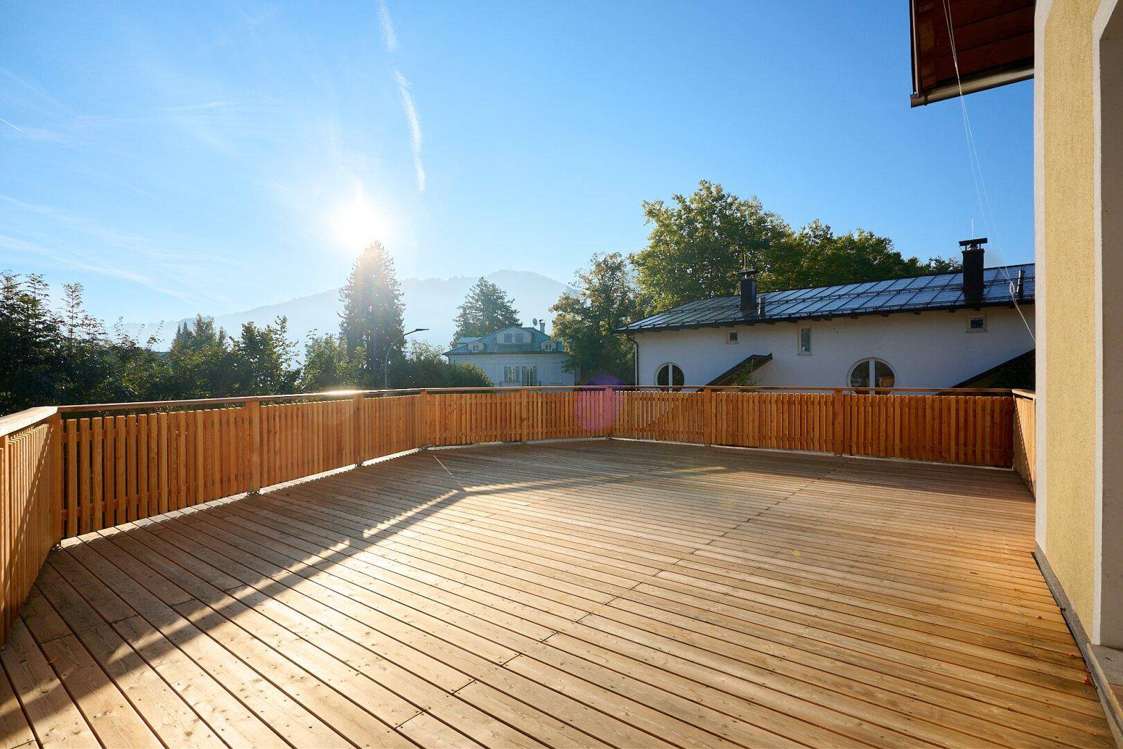 Sonnige Holzterrasse mit Bergblick und viel Platz für Entspannung im Freien.