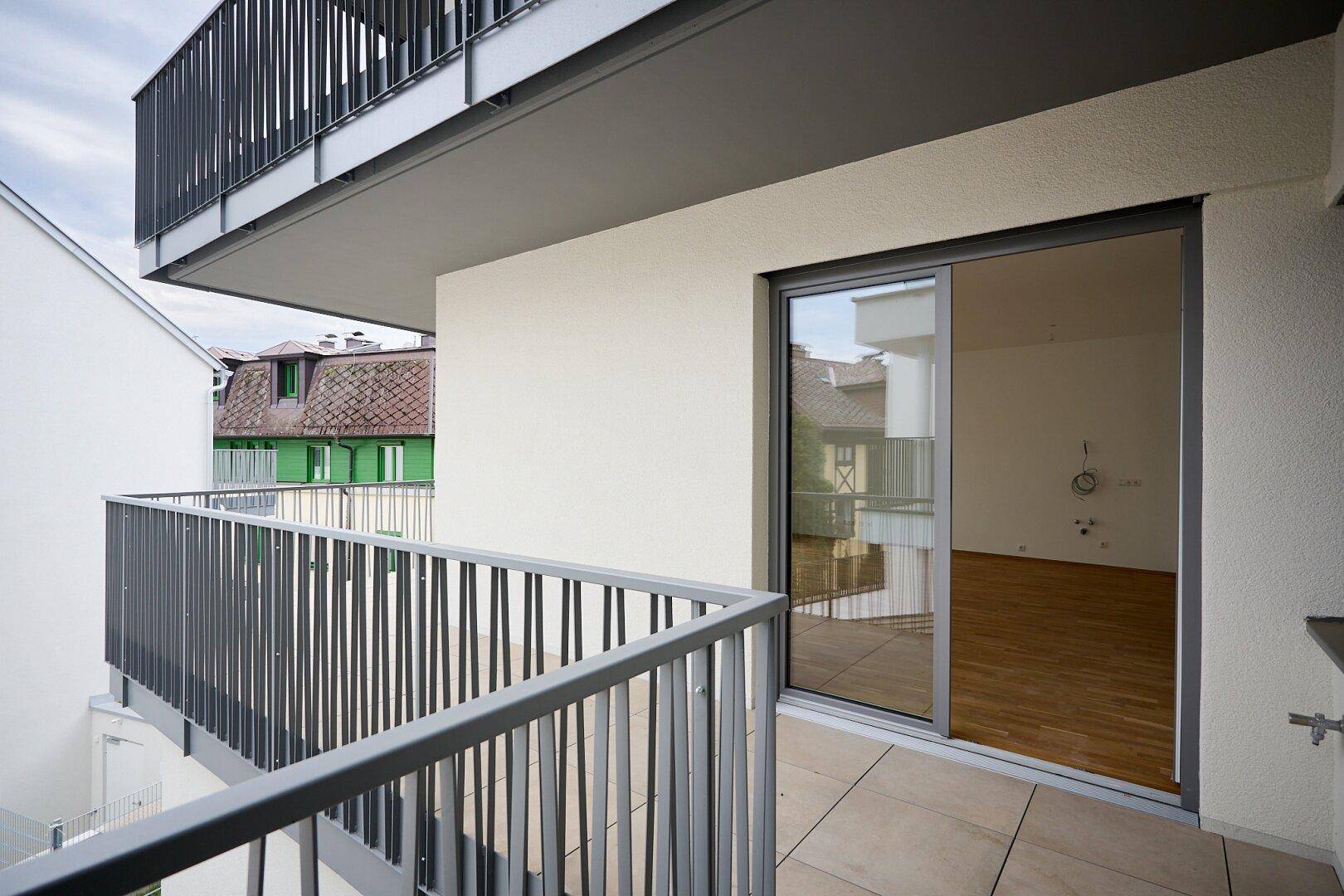 Balkon mit Fliesenboden und Schiebetür, die zum Innenbereich führt.