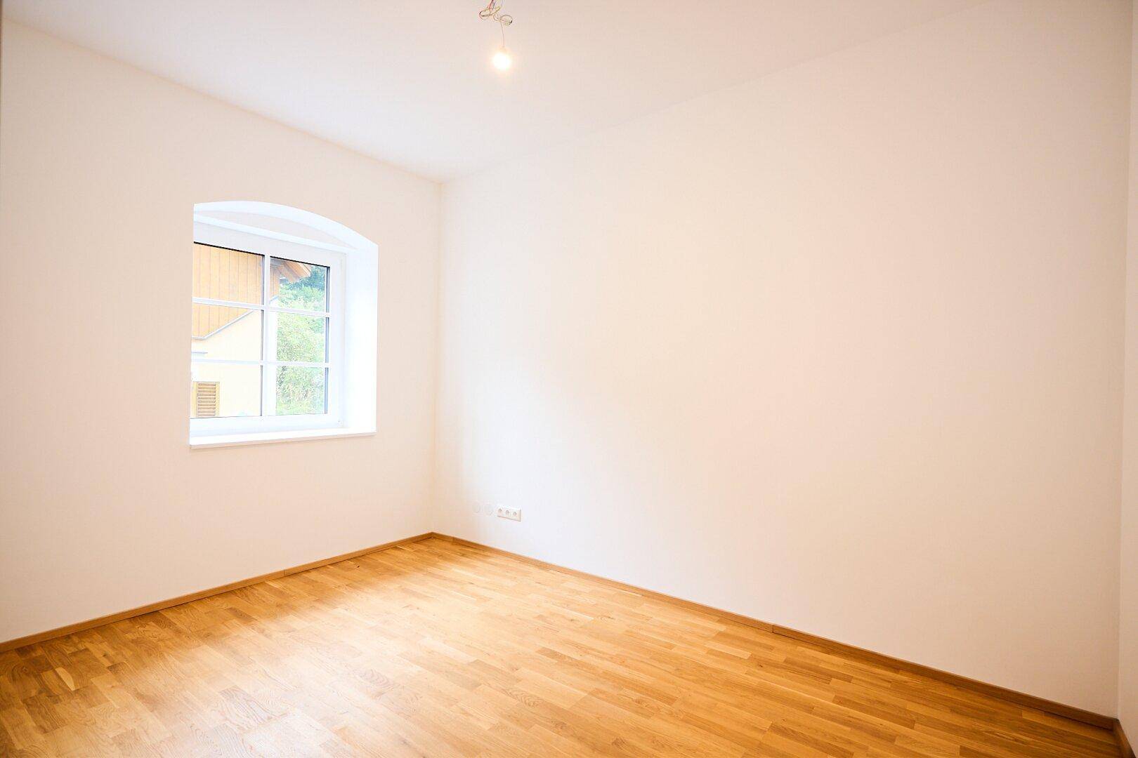 Gemütliches Zimmer mit Parkettboden und einem charmanten Bogenfenster.