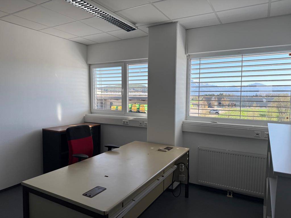 Helles Büro mit großem Schreibtisch und Fenstern, die eine weite Aussicht bieten.