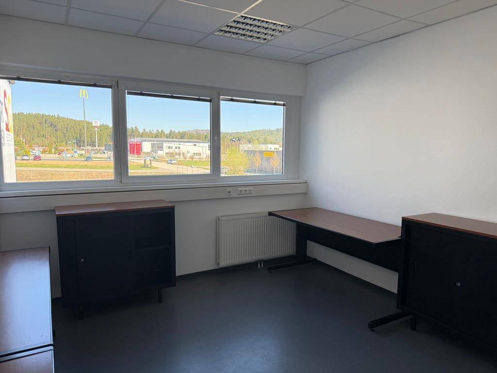 Büro mit dunklen Möbeln und Fenstern, die einen Blick auf die Umgebung ermöglichen.