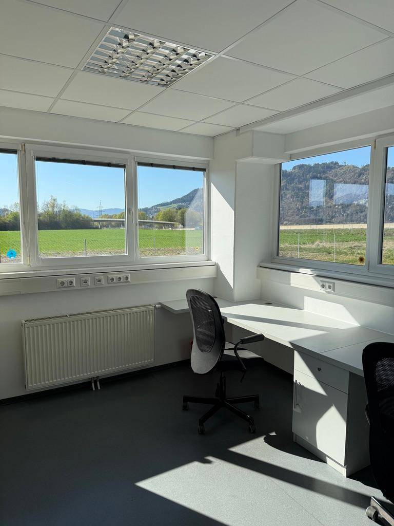 Geräumiges Büro mit Schreibtischen und Stühlen, viel Tageslicht und Blick ins Grüne.