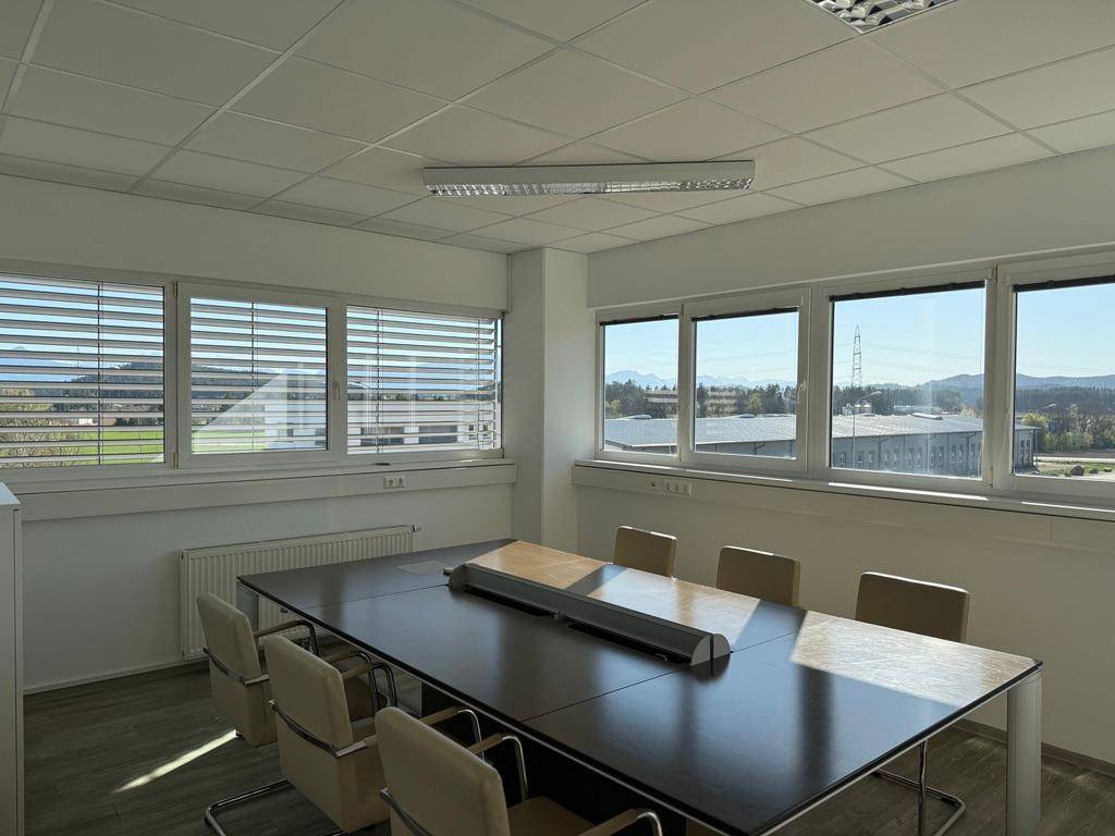 Heller Konferenzraum mit großem Tisch und Stühlen, bietet weite Aussicht auf die Landschaft.
