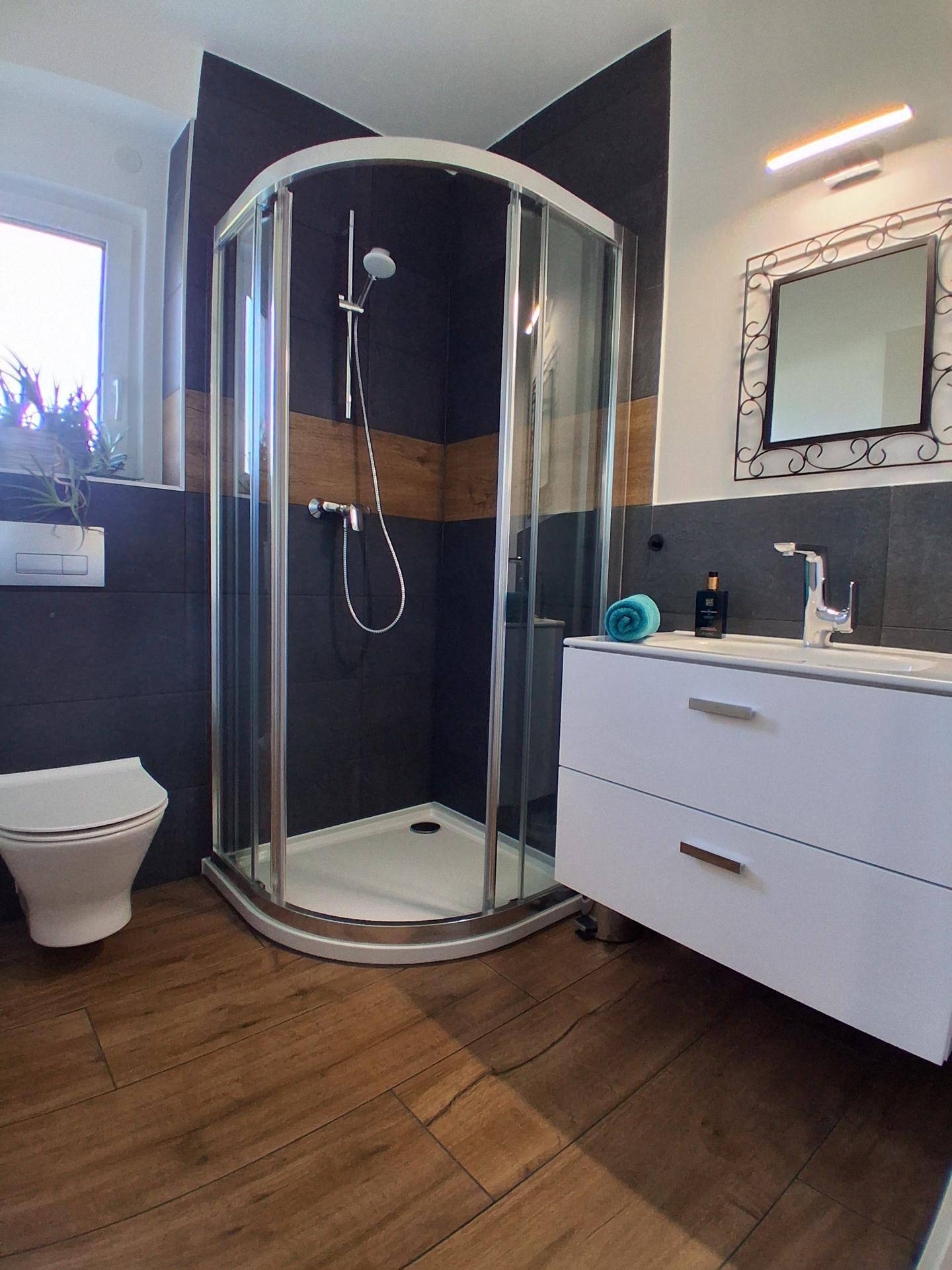 Modernes Badezimmer mit Duschkabine, Einzelwaschbecken und Fenster.