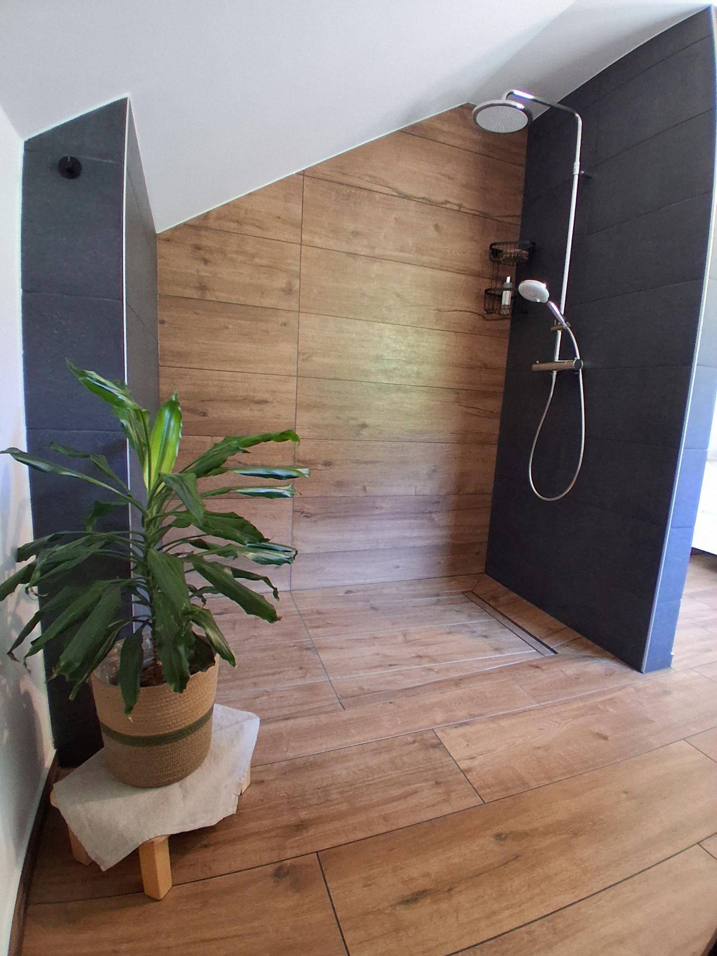 Geräumige begehbare Dusche mit modernen Fliesen und natürlichem Lichteinfall.