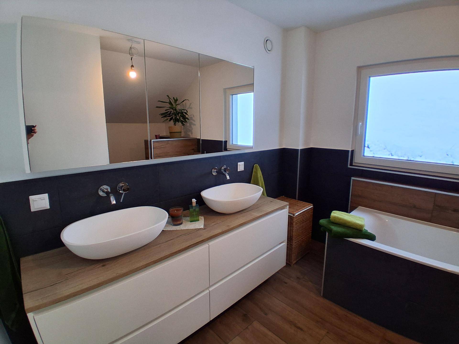 Modernes Badezimmer mit Doppelwaschbecken, Badewanne und großem Spiegelschrank.