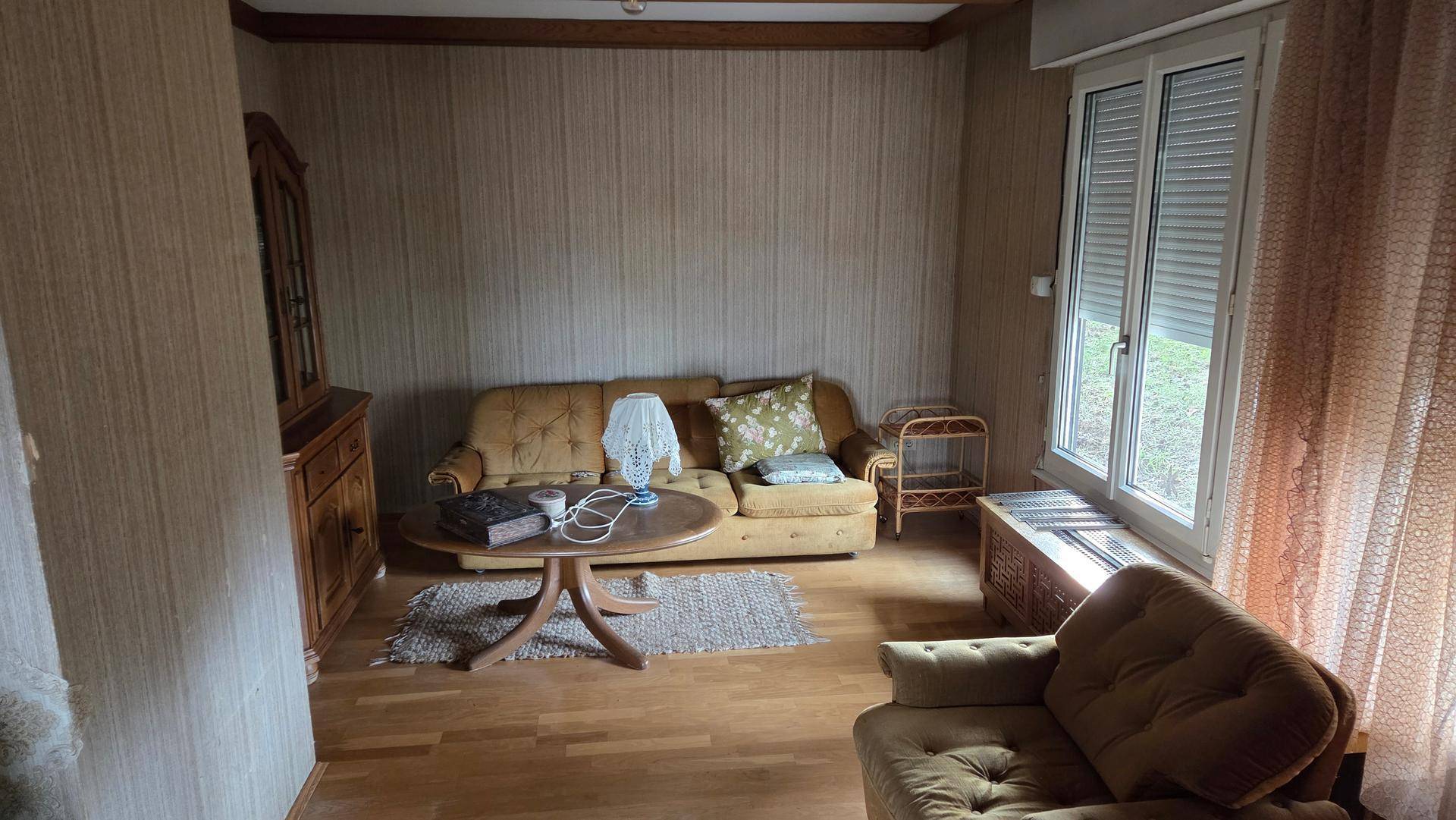 Gemütliches Wohnzimmer mit Sofa, Couchtisch, Holzfußboden und gemusterter Tapete.