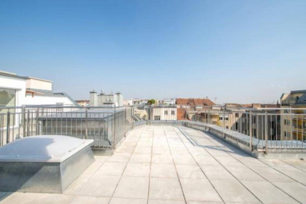 Weitläufige Dachterrasse mit Stadtblick und Fliesenboden, umgeben von Metallgeländern.