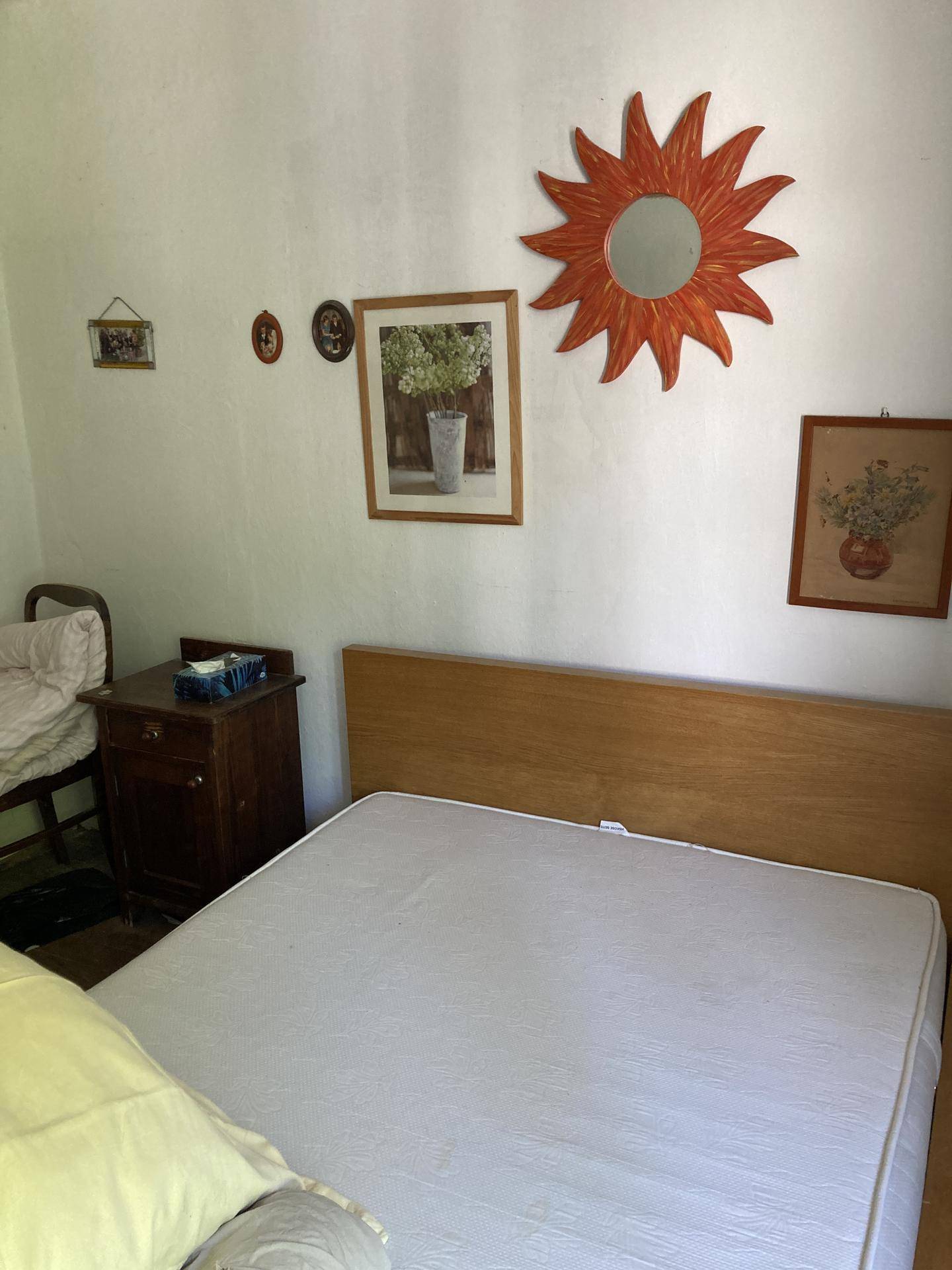 Schlafzimmer mit weiß gestrichenen Wänden, einem Holzbettrahmen und rustikaler Dekoration.