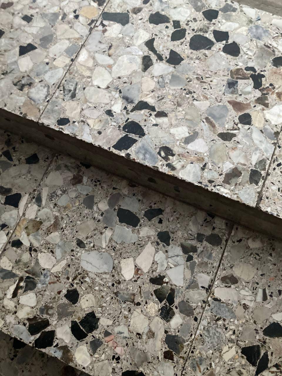 Treppenstufen aus mehrfarbigem Terrazzo mit verschiedenen Steinfragmenten, die eine robuste Oberfläche bilden.