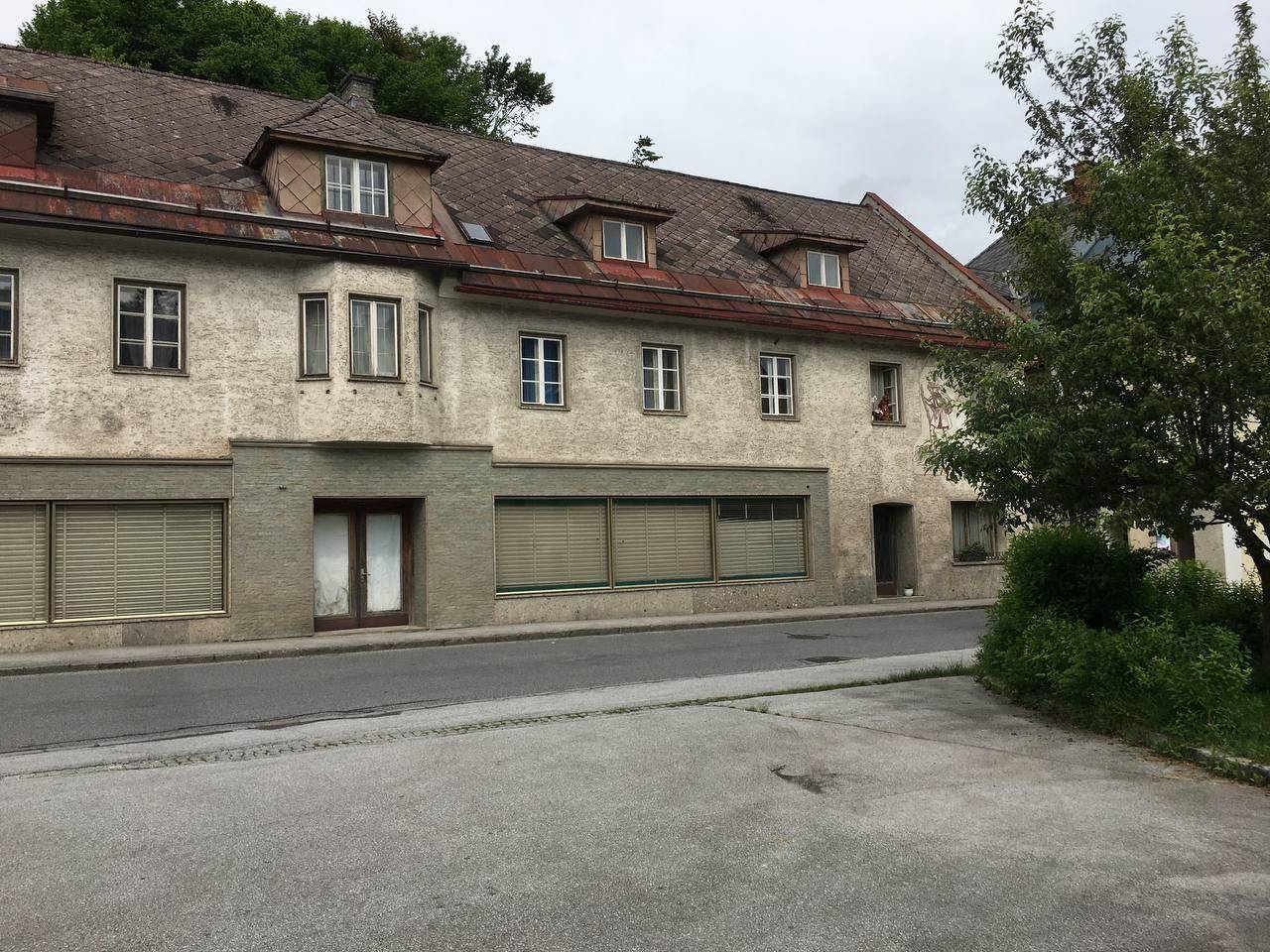 Historisches Gebäude mit traditioneller Fassade, Dachgauben und Geschäften im Erdgeschoss an einer Straße.