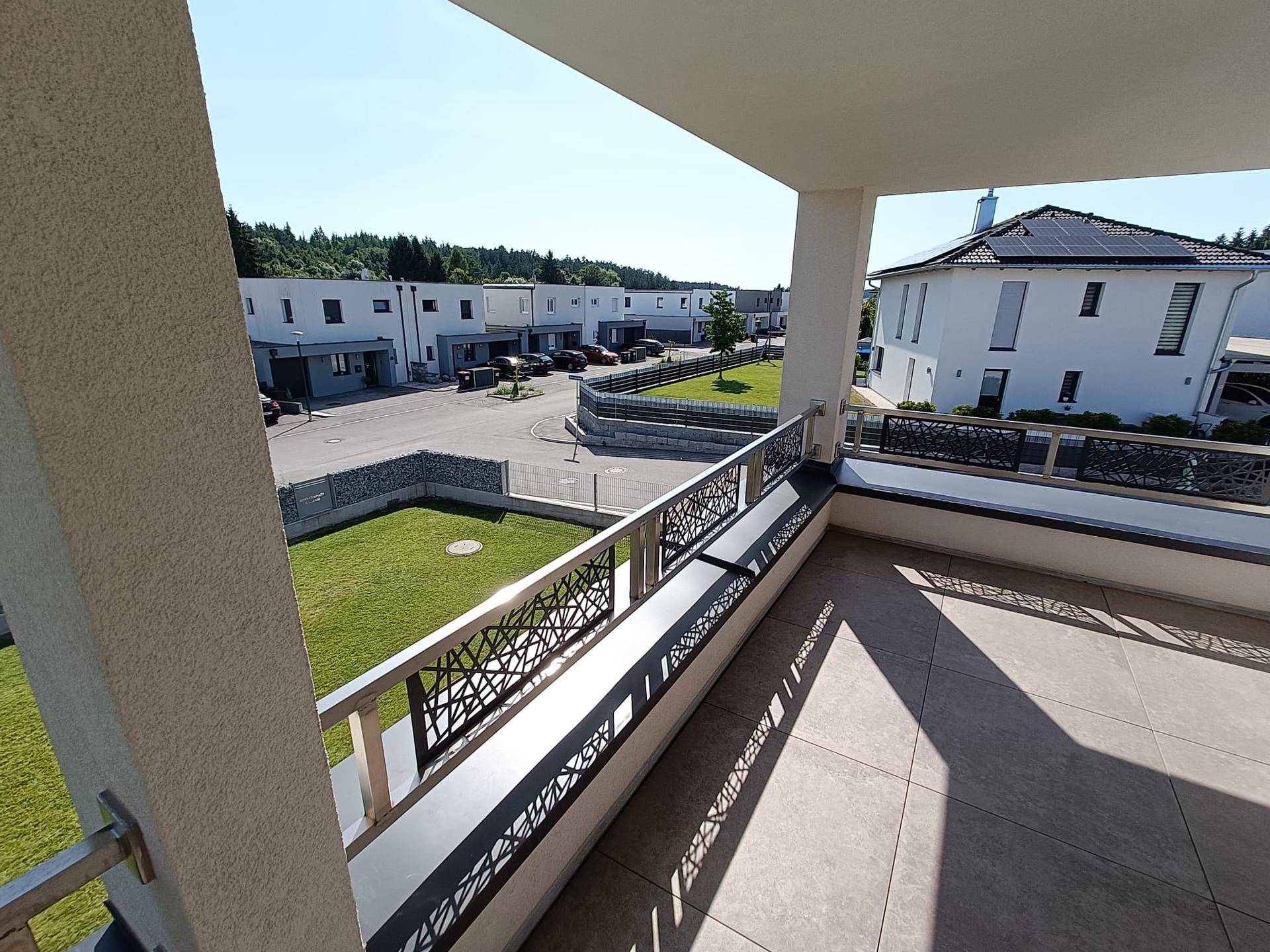 Geräumiger Balkon mit Fliesenboden und modernem Geländer, bietet Blick auf die Nachbarschaft.