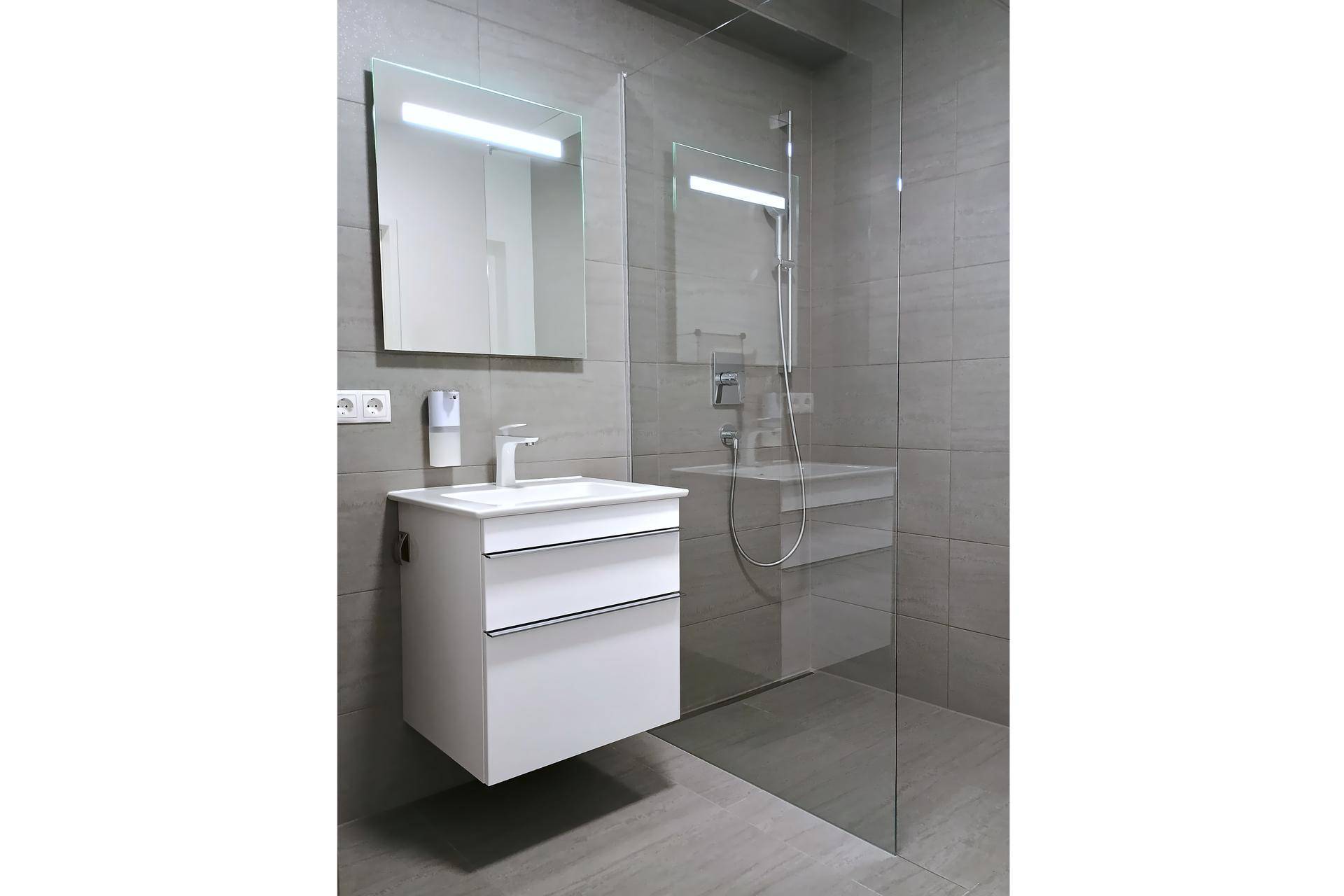 Modernes Badezimmer mit begehbarer Dusche, Waschbecken und eleganten grauen Fliesen.
