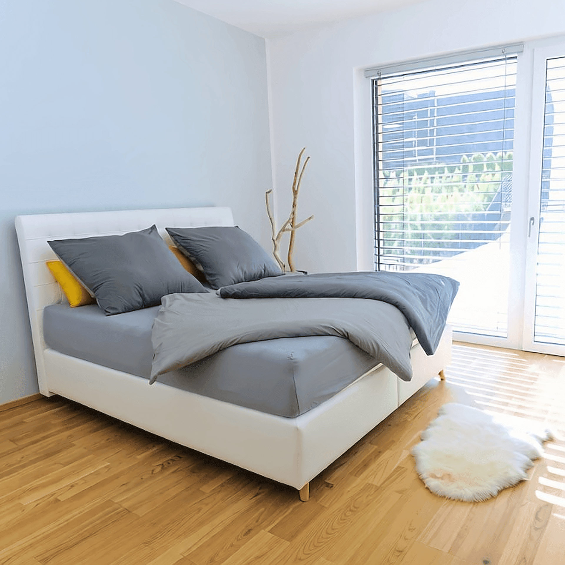 Helles Schlafzimmer mit Holzboden, großem Fenster und modernem Bett für erholsame Nächte.