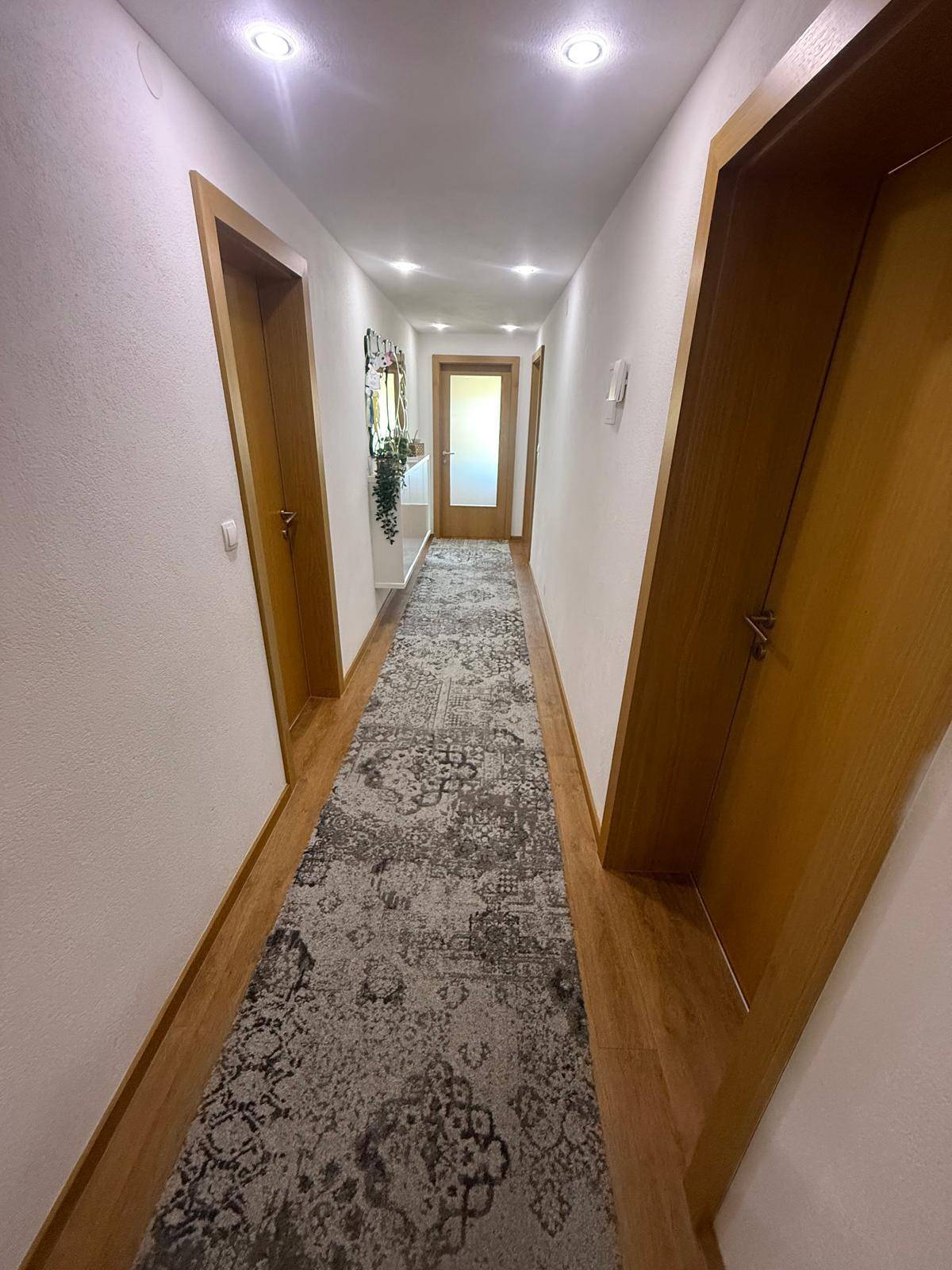 Heller Flur mit Laminatboden, Holzrahmen und Einbaustrahlern an der Decke.