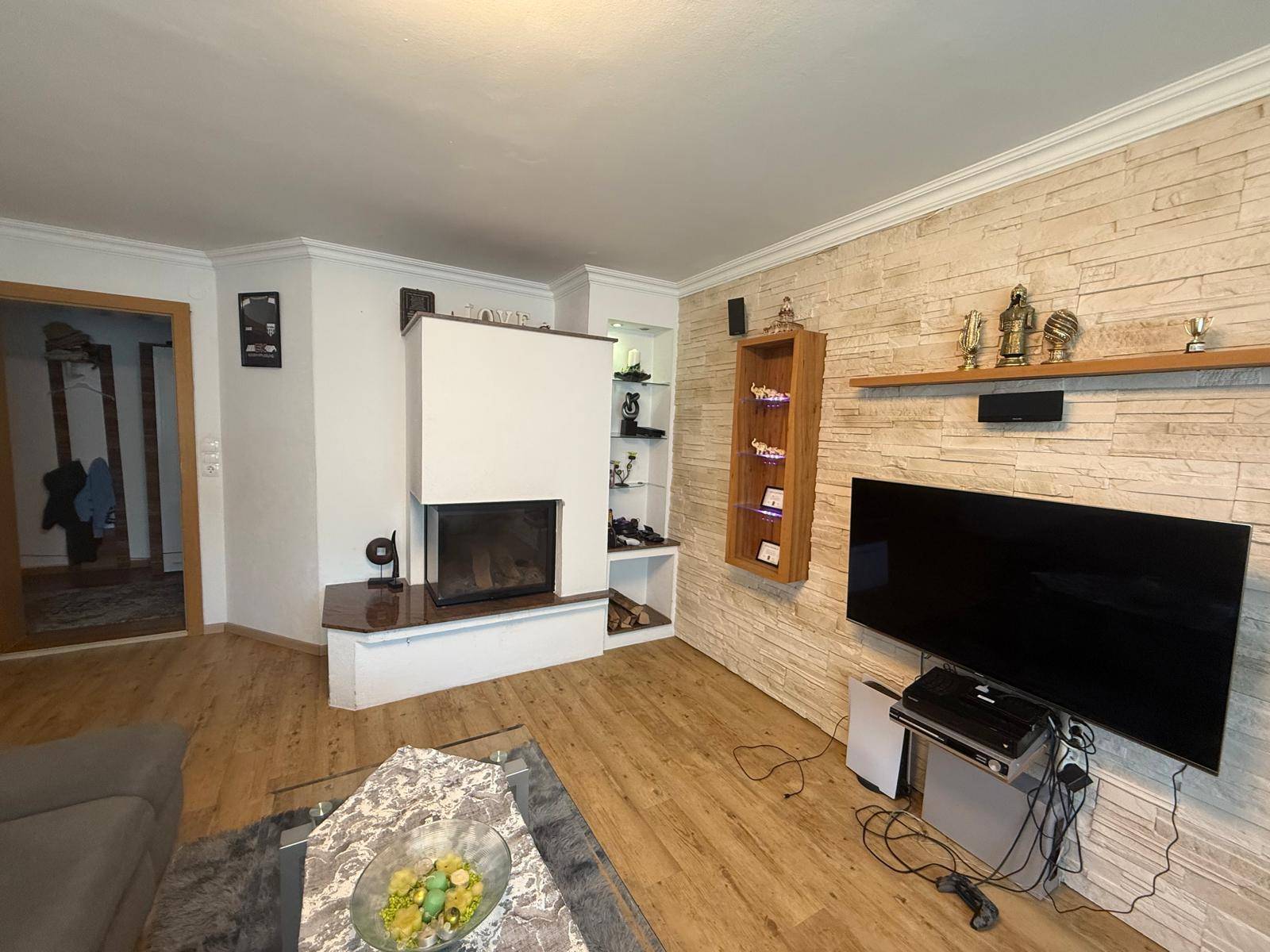 Helles Wohnzimmer mit modernem Kamin, dekorativer Steinwand und Laminatboden.