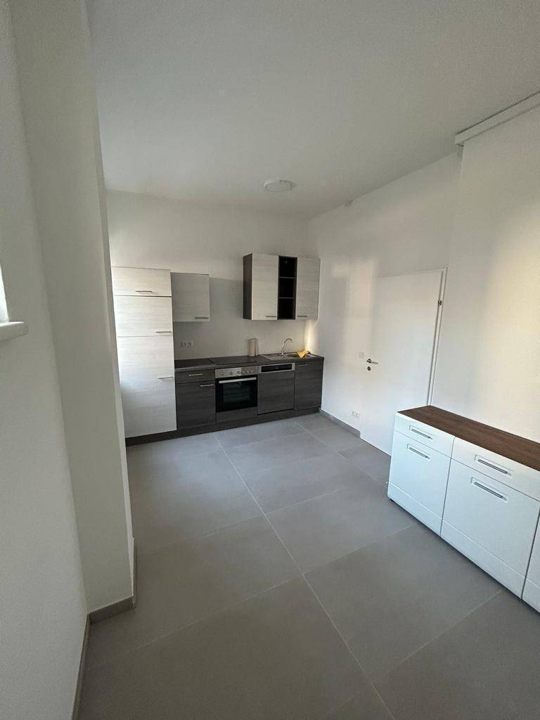 Geräumige Küche mit moderner Einbauküche, grauen Fliesen und einem zusätzlichen Sideboard für Stauraum.