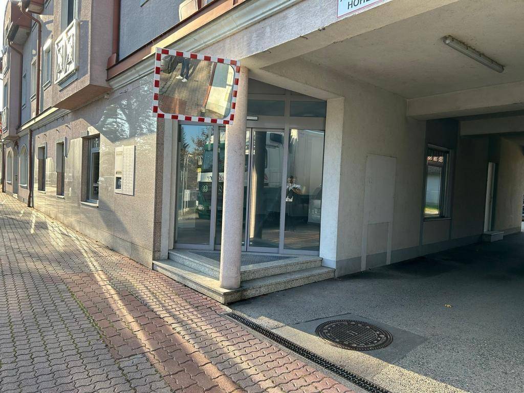 Eingangsbereich eines modernen Gebäudes mit Glasfassade und einem Verkehrsspiegel an der Ecke.