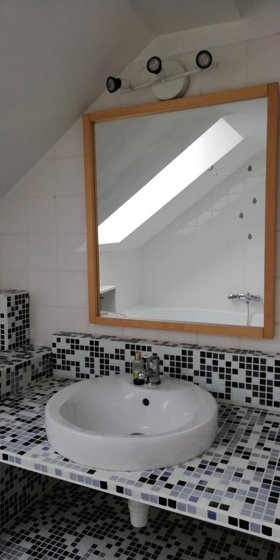 Badezimmer mit modernem Aufsatzwaschbecken, großem Spiegel und auffälligen Mosaikfliesen unter einer Dachschräge.