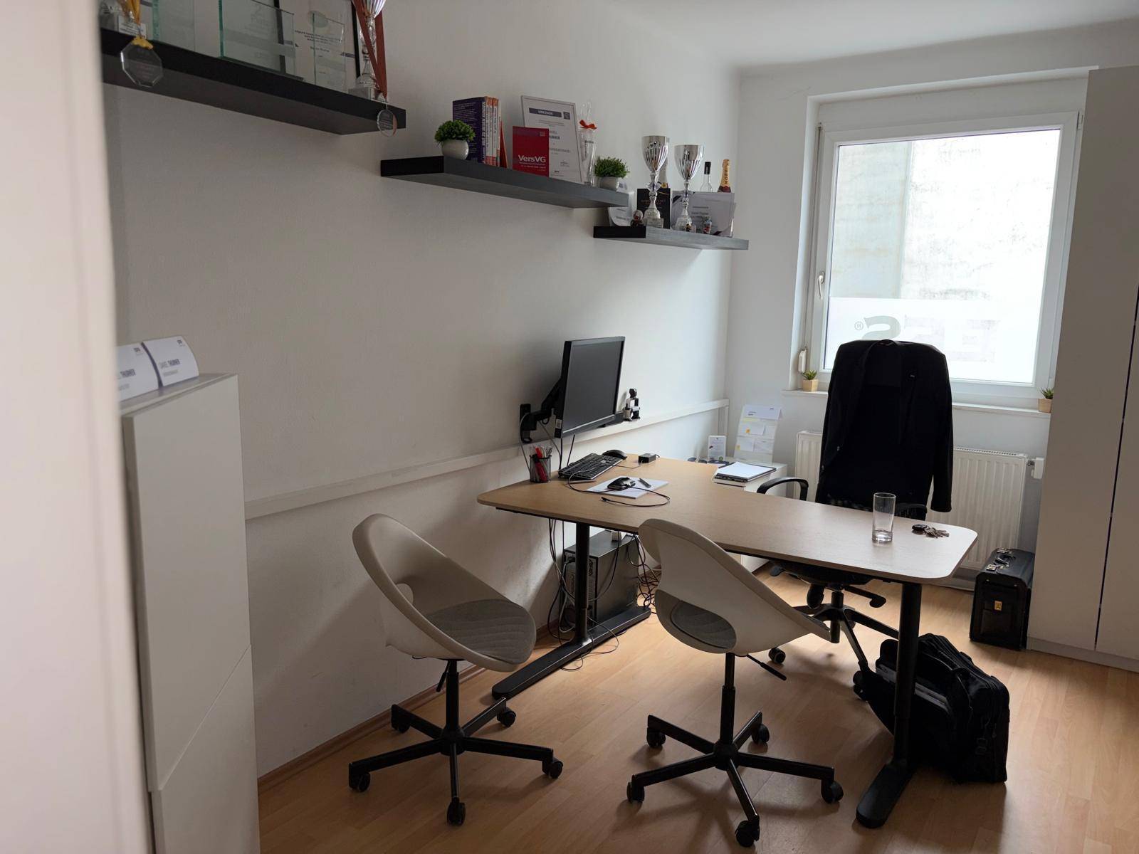 Kompaktes Büro mit Schreibtisch, Regalen und einem Fenster, ideal für Einzelarbeit oder als kleines Besprechungszimmer.