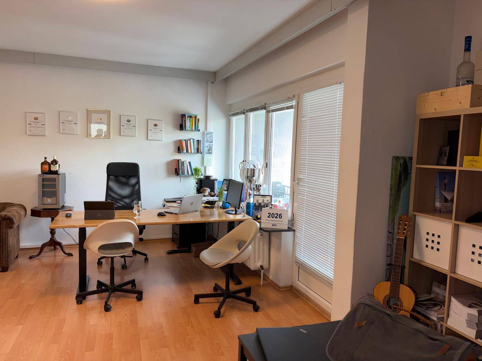Helles Büro mit mehreren Arbeitsplätzen, Regalen und einem Chesterfield-Sofa, ideal für kreatives Arbeiten und Besprechungen.