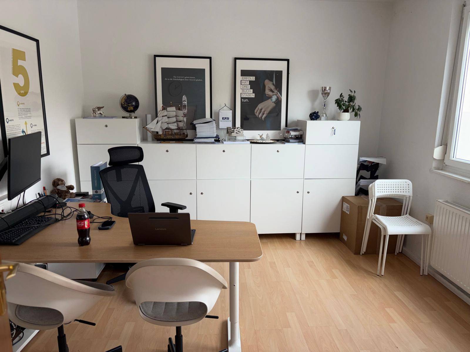 Funktionales Büro mit weißen Schränken, großem Schreibtisch und ergonomischem Stuhl, ideal für konzentriertes Arbeiten.