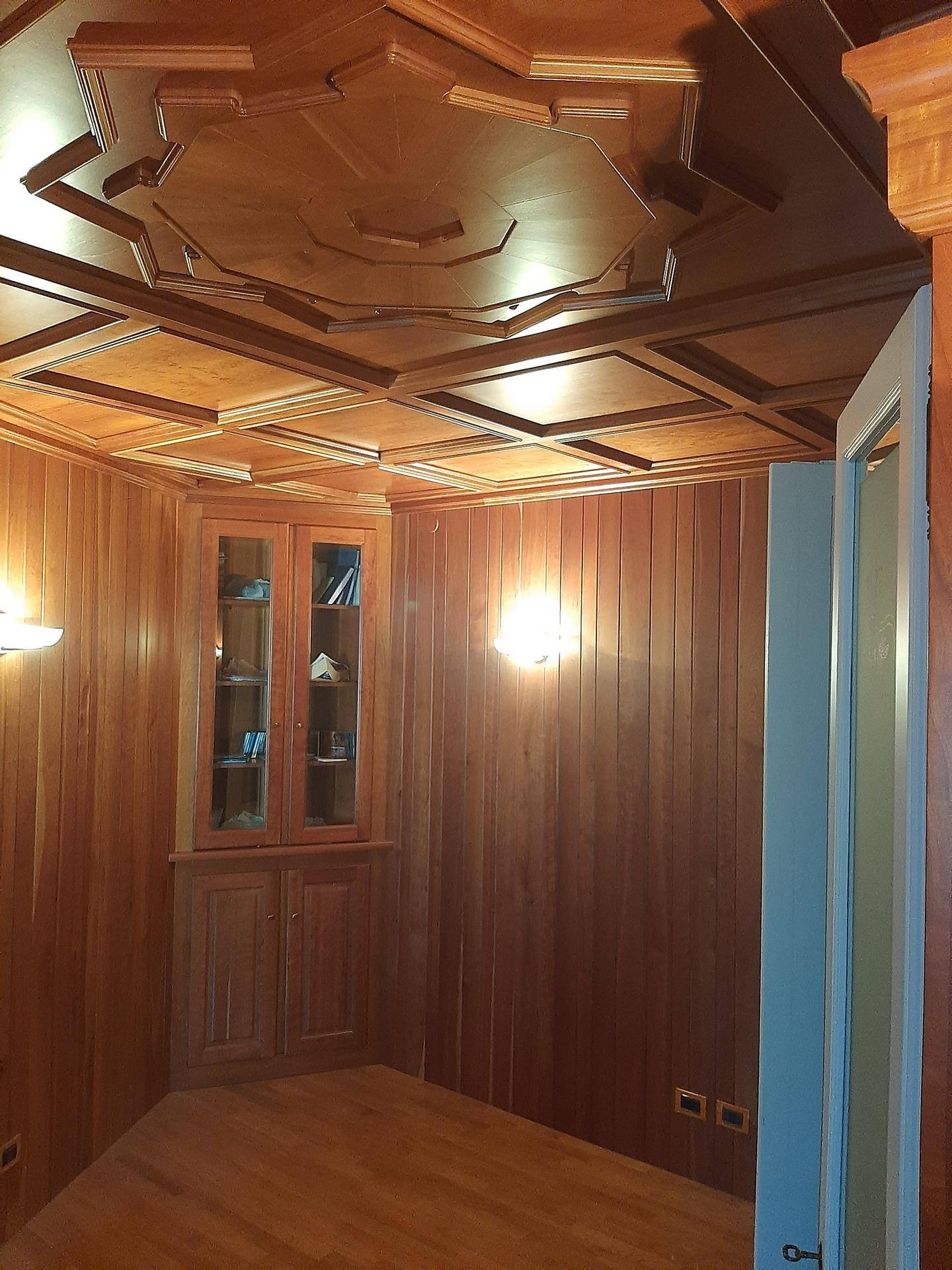Raum mit aufwendiger Holzvertäfelung an Wänden und Decke sowie einem eingebauten Eckschrank.