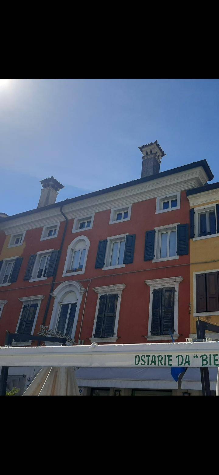 Detailansicht der historischen roten Gebäudefassade mit geschlossenen Fensterläden und einem Restaurantbereich.