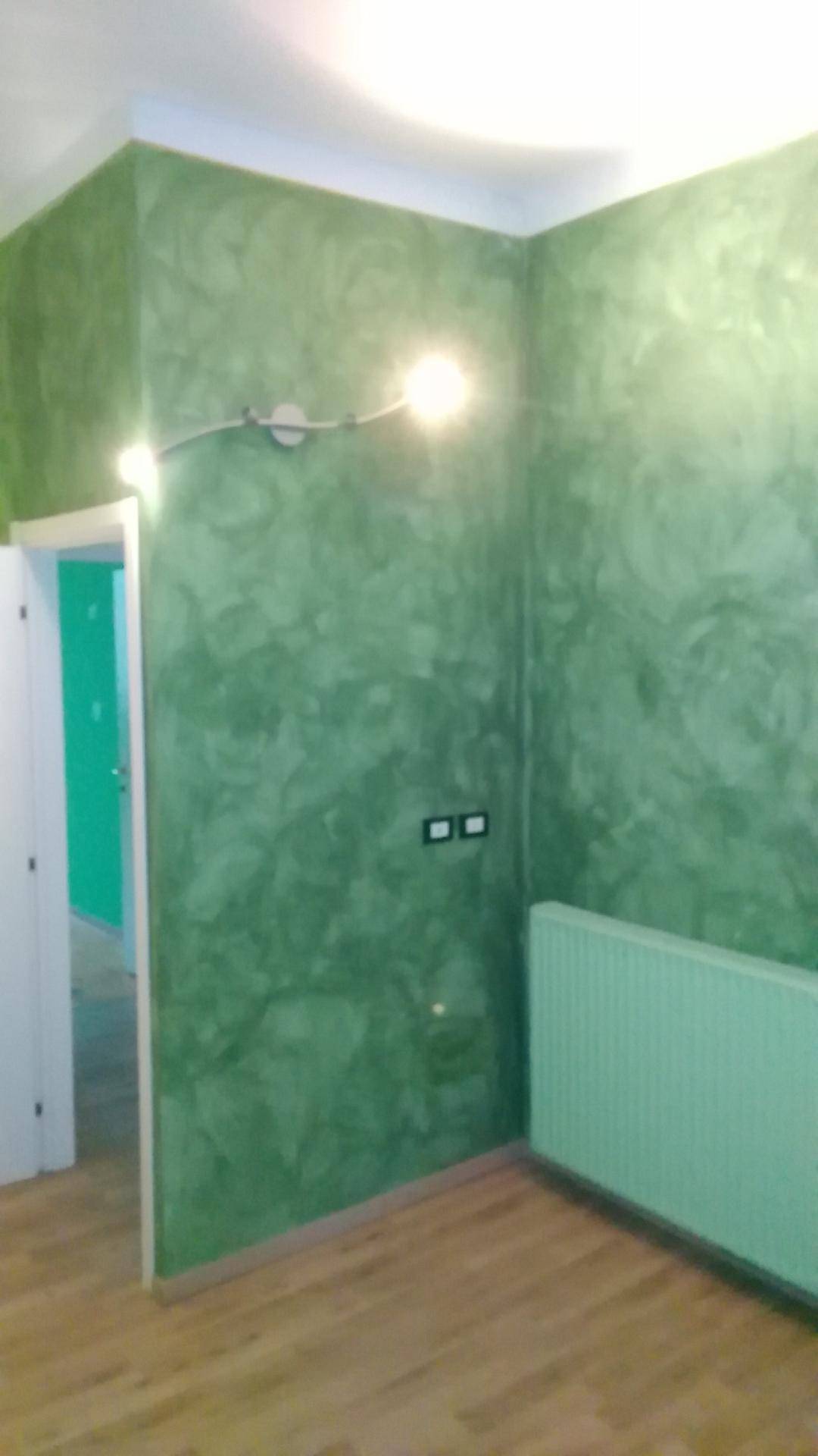 Raum mit auffälligen grünen Wänden in Spachteltechnik und einem passenden Heizkörper.