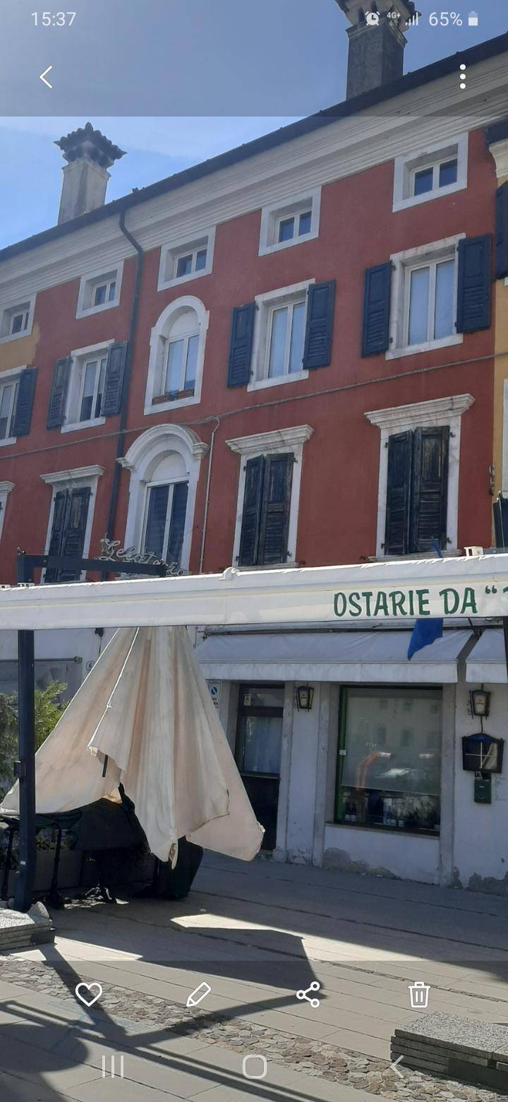 Historische Fassade eines Gebäudes mit roten Wänden, blauen Fensterläden und einem Restaurant im Erdgeschoss.