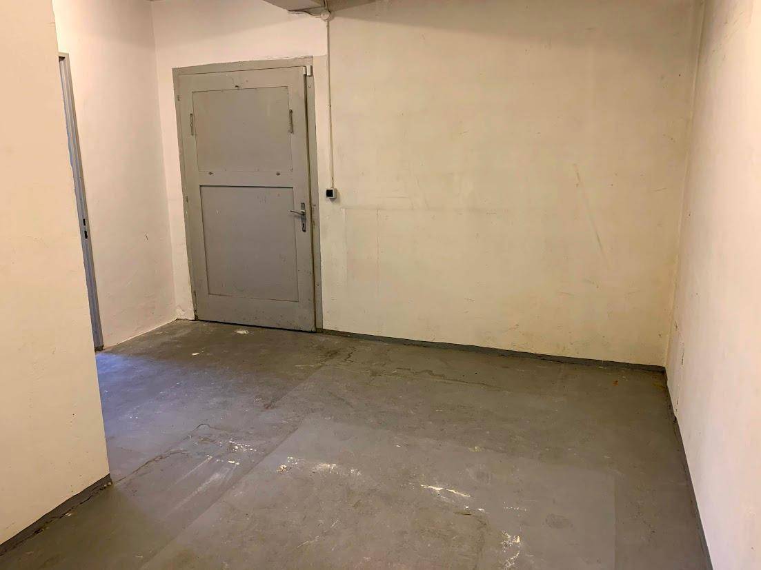 Einfacher Lagerraum mit Betonboden und weißen Wänden, ideal für Abstellzwecke.
