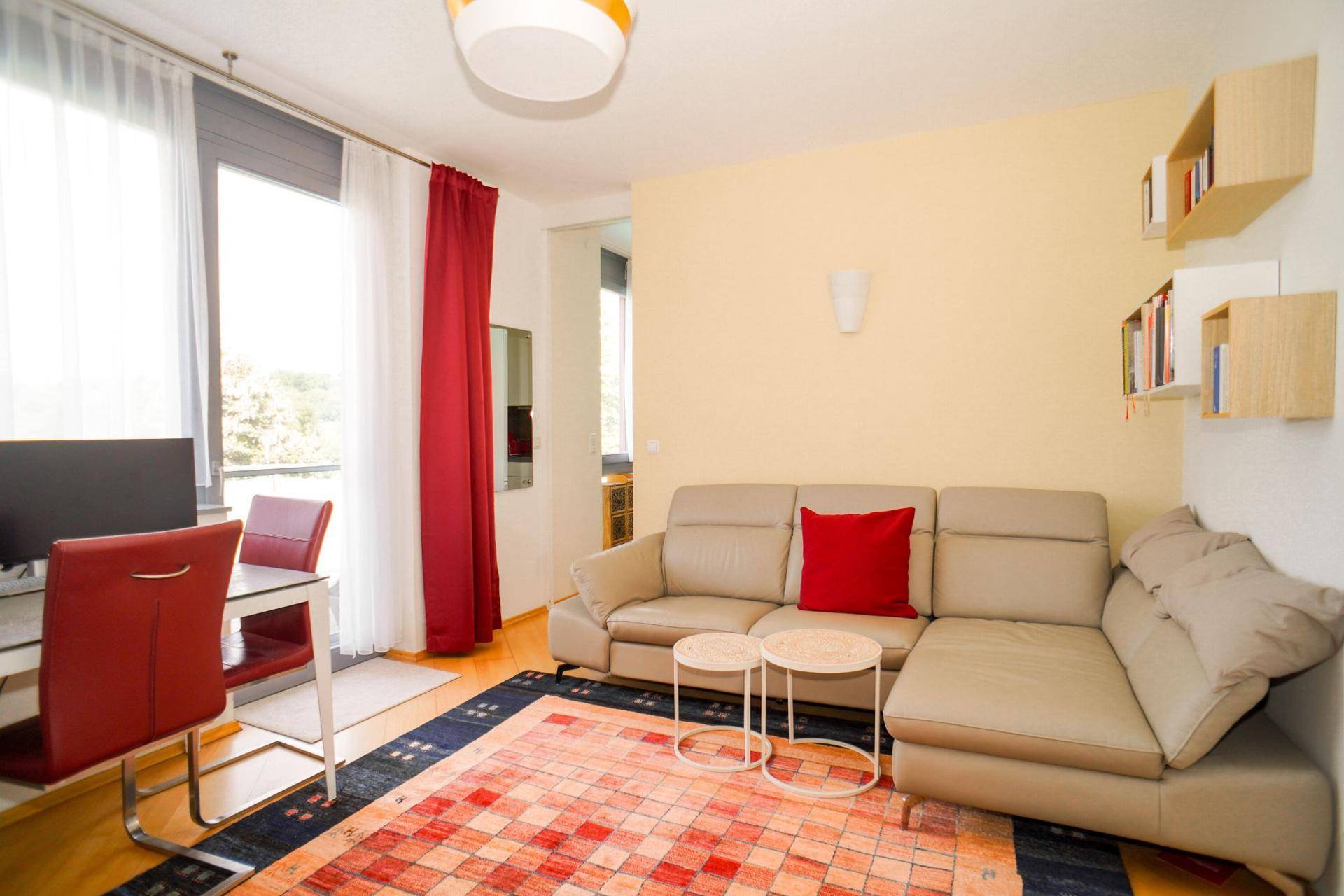 Gemütlicher Wohnbereich mit Sofa, Teppich und großem Fenster für viel Tageslicht.