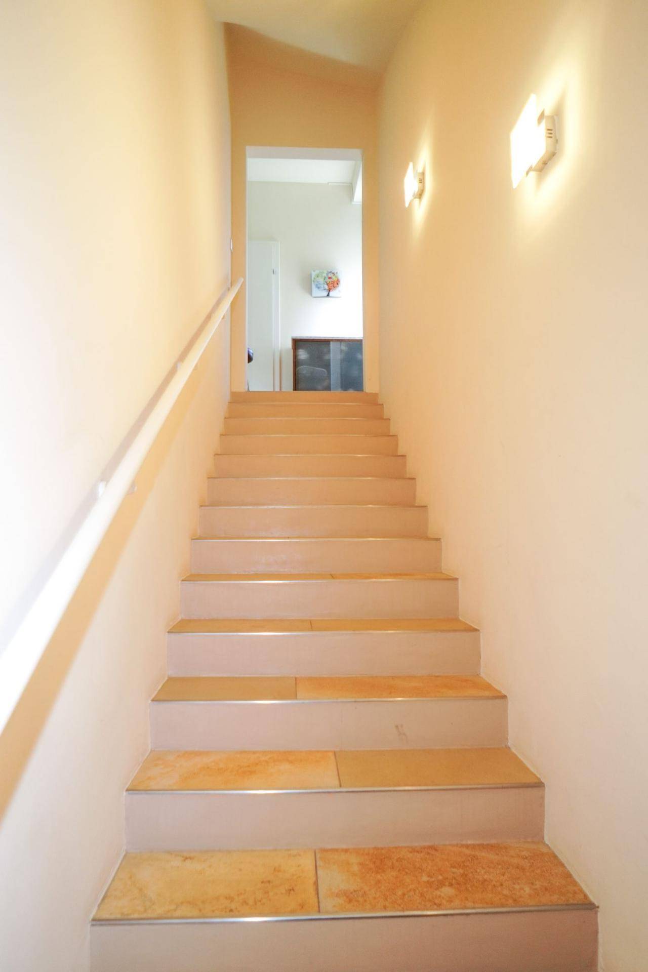 Helle Treppe mit beigen Wänden führt in die obere Etage des Hauses.