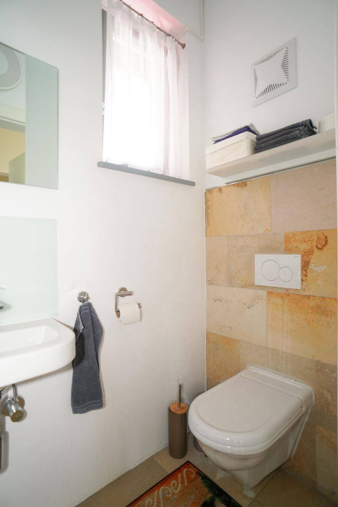 Modernes Gäste-WC mit Wand-WC, Waschbecken und Fenster für Tageslicht.