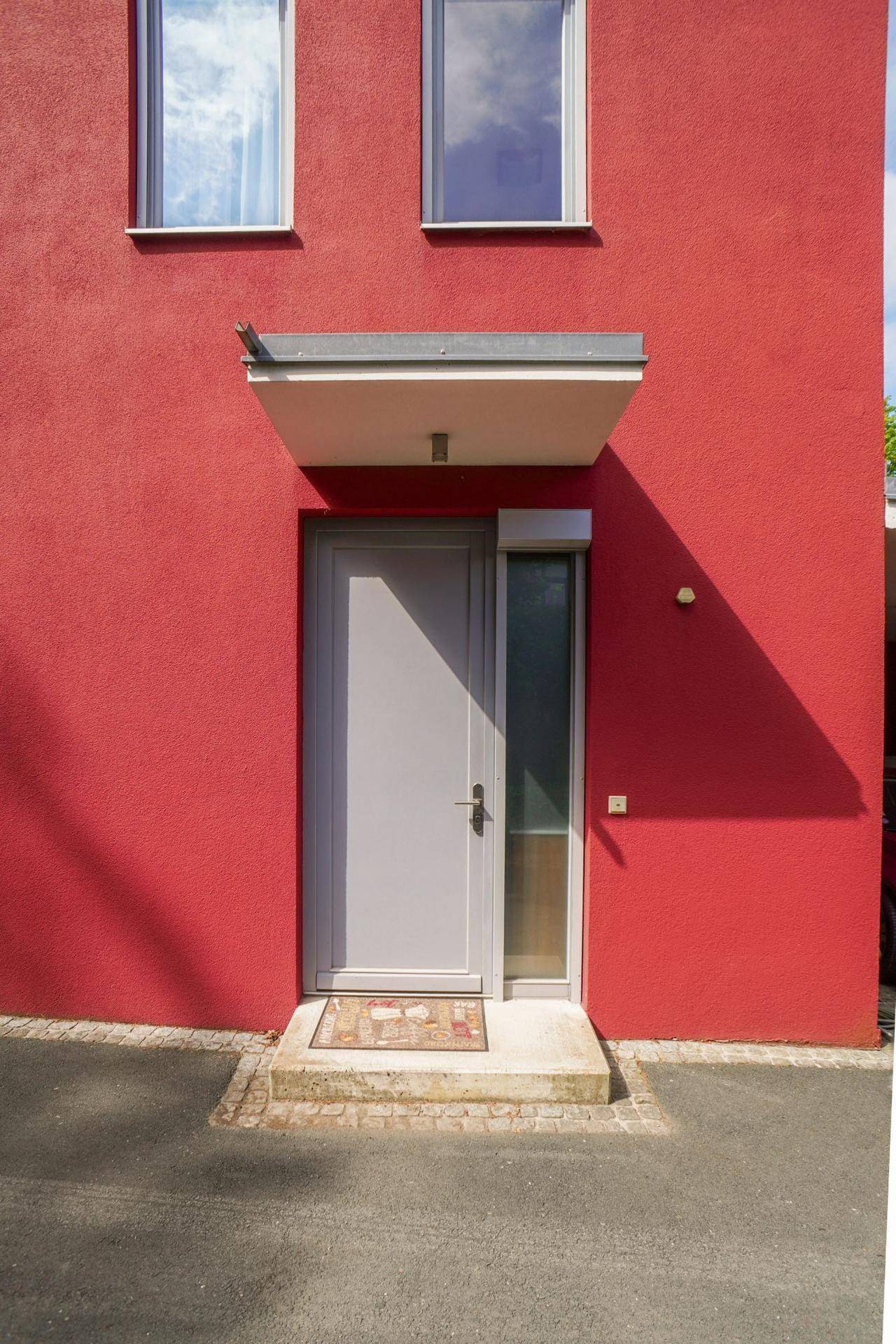 Haupteingang des modernen Hauses mit heller Tür und Vordach.