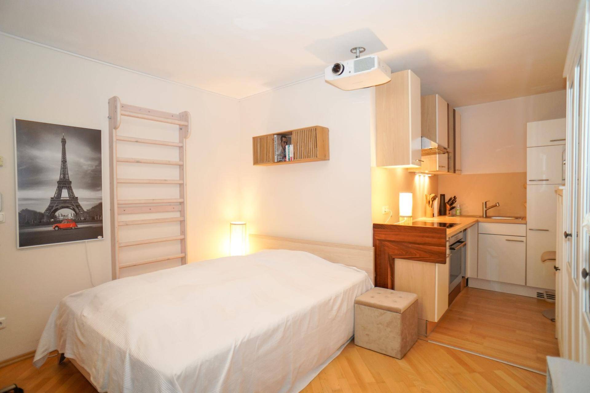 Schlafzimmer im Untergeschoss mit integrierter Küchenzeile und Projektor an der Decke.